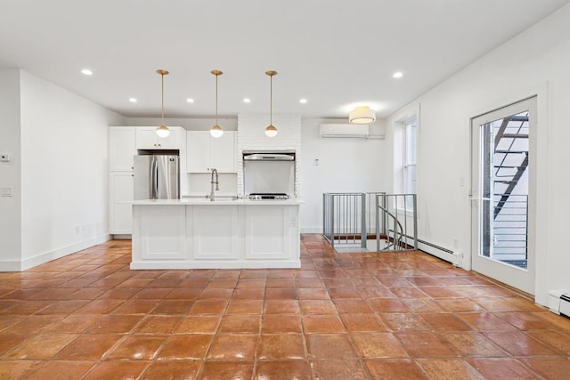 kitchen featuring a baseboard radiator, light countertops, hanging light fixtures, freestanding refrigerator, and a sink