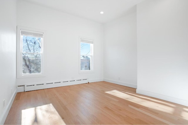 unfurnished room with a baseboard heating unit, recessed lighting, light wood-style floors, and baseboards