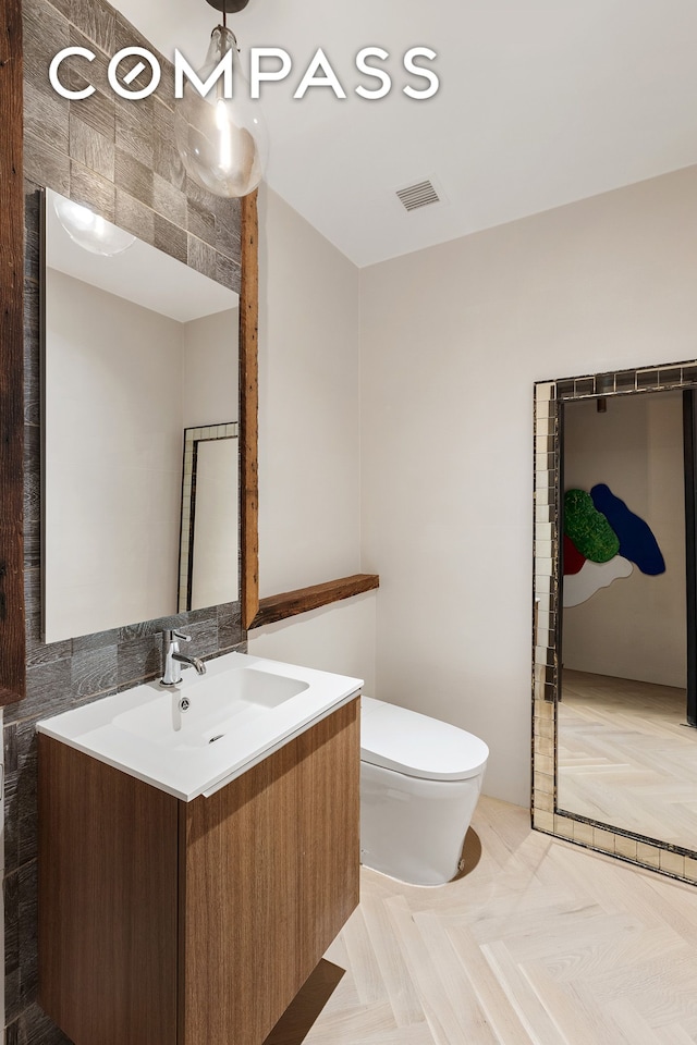 bathroom with visible vents, vanity, and toilet