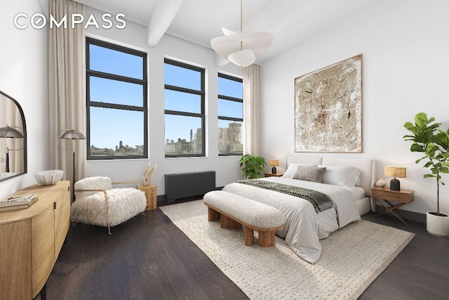 bedroom with beamed ceiling, radiator, hardwood / wood-style floors, and a towering ceiling