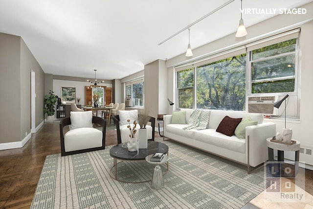 living room featuring baseboards, cooling unit, and a notable chandelier