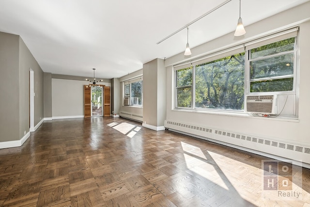 unfurnished living room featuring baseboards, a chandelier, baseboard heating, and cooling unit