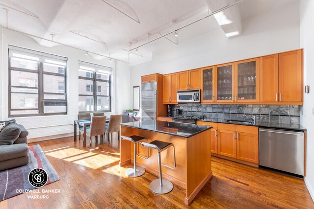 kitchen featuring tasteful backsplash, hardwood / wood-style floors, a center island, a breakfast bar, and stainless steel appliances