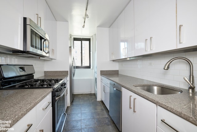 kitchen featuring white cabinets, backsplash, appliances with stainless steel finishes, and a sink