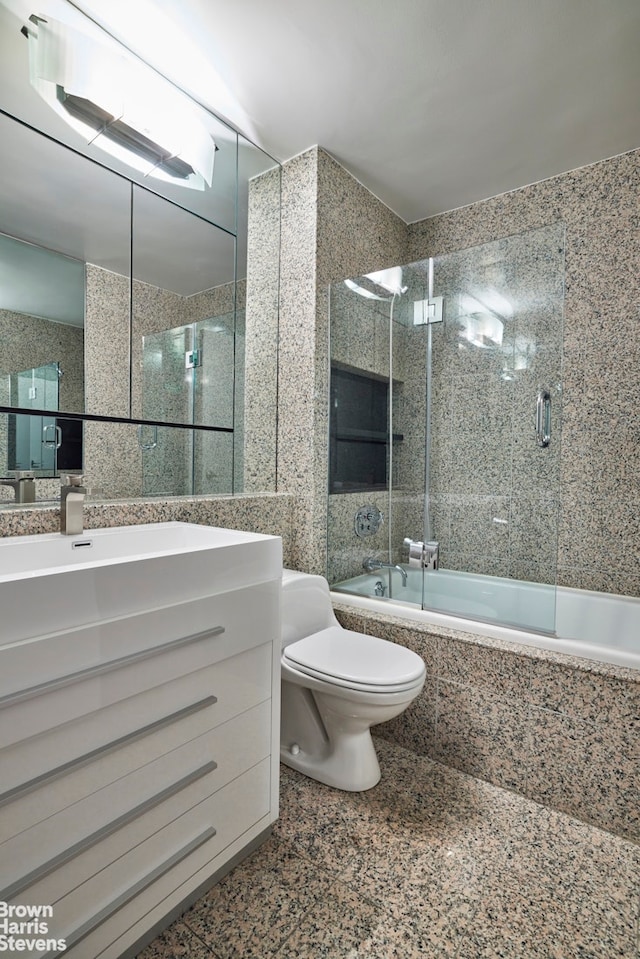 full bathroom with tiled shower / bath, toilet, tile walls, and vanity