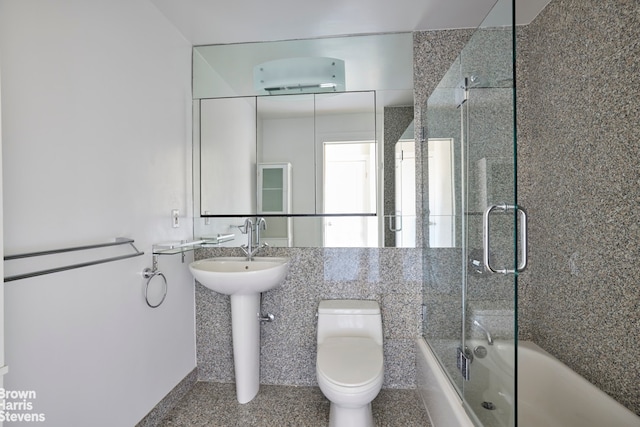 bathroom featuring a sink, toilet, and bath / shower combo with glass door