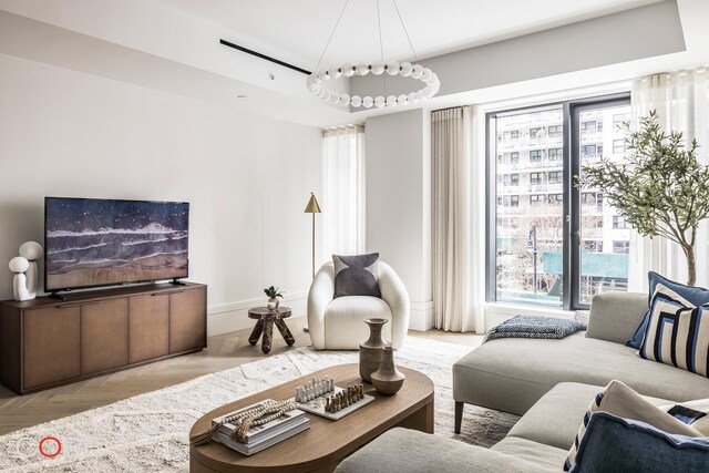 living room with light parquet floors, a wealth of natural light, and a raised ceiling