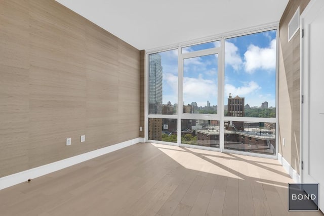 spare room featuring a wall of windows and wood-type flooring