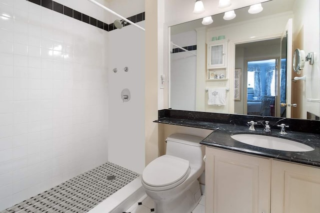 bathroom with toilet, tiled shower, crown molding, and vanity