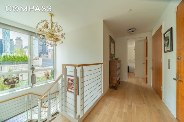 corridor with light hardwood / wood-style flooring, plenty of natural light, and an inviting chandelier