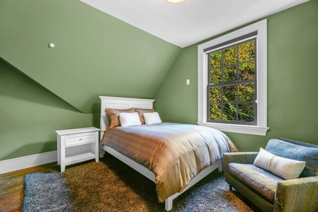 bedroom with vaulted ceiling and dark hardwood / wood-style flooring