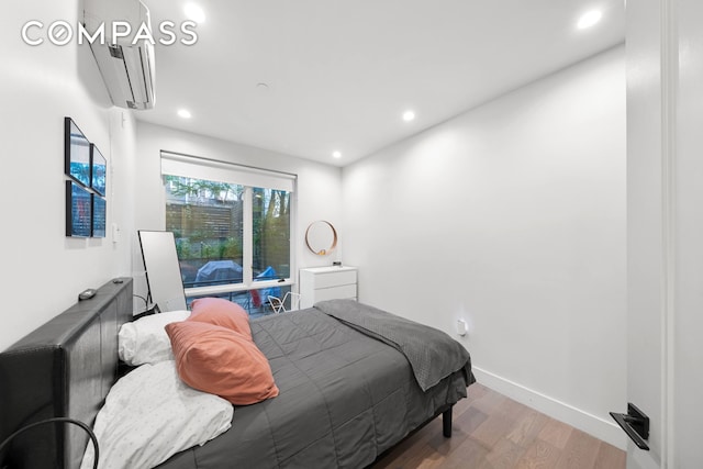 bedroom featuring baseboards, a wall mounted air conditioner, wood finished floors, and recessed lighting