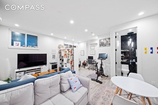 living room with recessed lighting, light wood finished floors, and a wall mounted AC