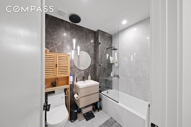 bathroom featuring bathtub / shower combination, toilet, visible vents, vanity, and tile walls