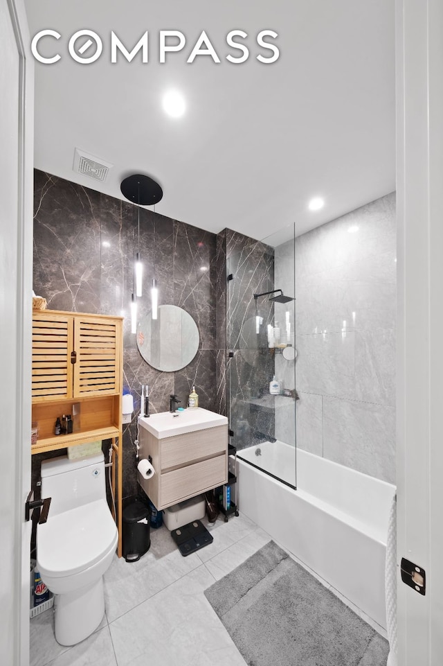 bathroom with visible vents, toilet, a combined bath / shower with rainfall shower, vanity, and tile walls