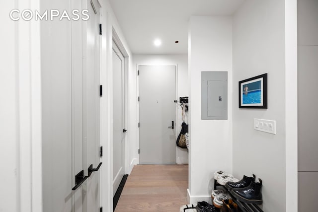 hallway featuring electric panel, light wood-style flooring, and baseboards