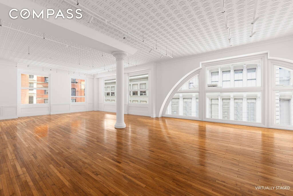 unfurnished living room featuring wood-type flooring and ornamental molding