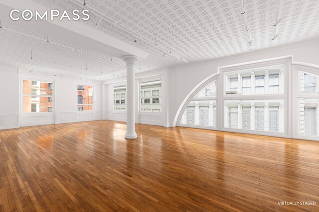 unfurnished living room featuring wood-type flooring and ornamental molding