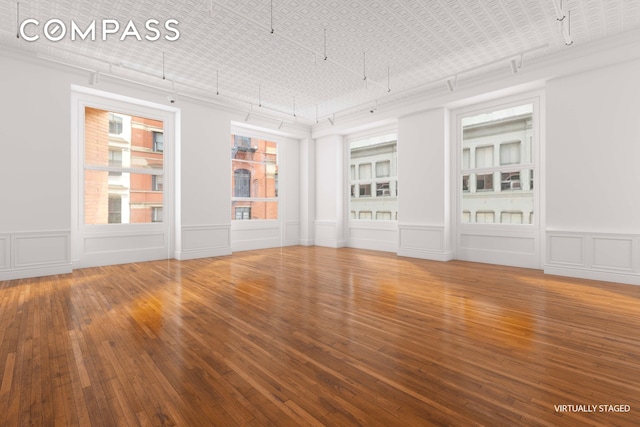 spare room featuring hardwood / wood-style flooring, an ornate ceiling, and a decorative wall