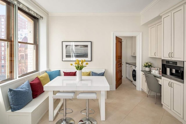 dining area with breakfast area, light tile patterned floors, washer / dryer, and ornamental molding