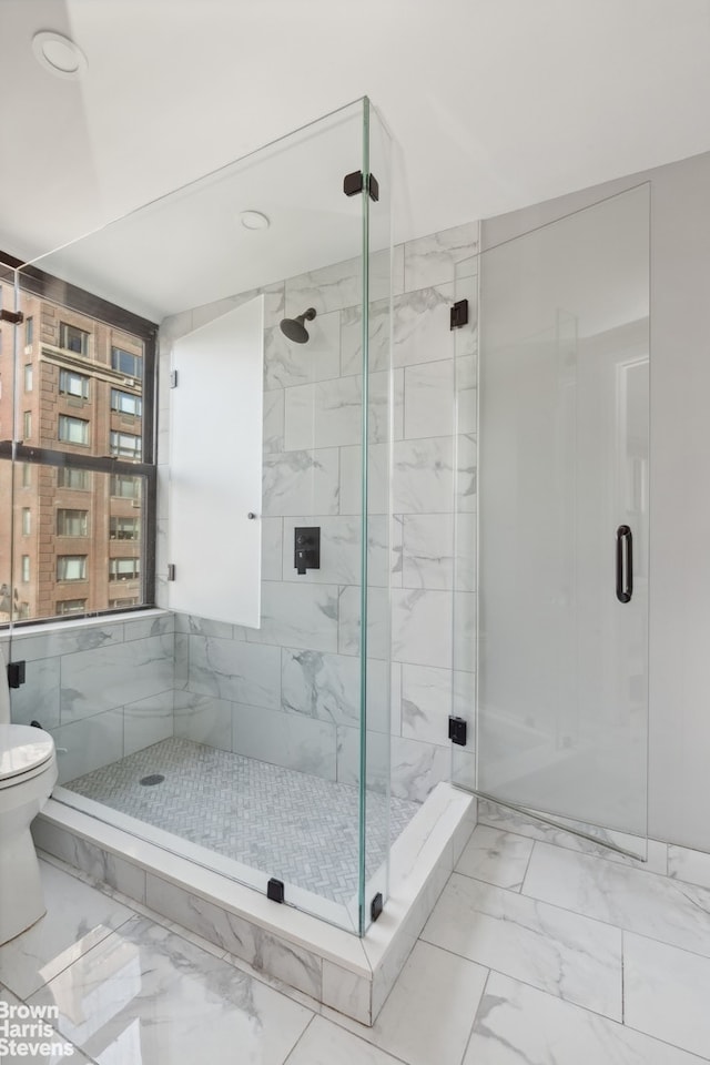 bathroom featuring a shower stall, toilet, and marble finish floor