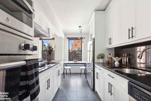 kitchen featuring a sink, tasteful backsplash, dark countertops, stainless steel appliances, and white cabinets