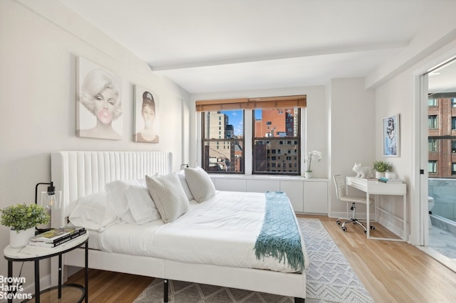 bedroom with wood finished floors, beamed ceiling, multiple windows, and radiator heating unit