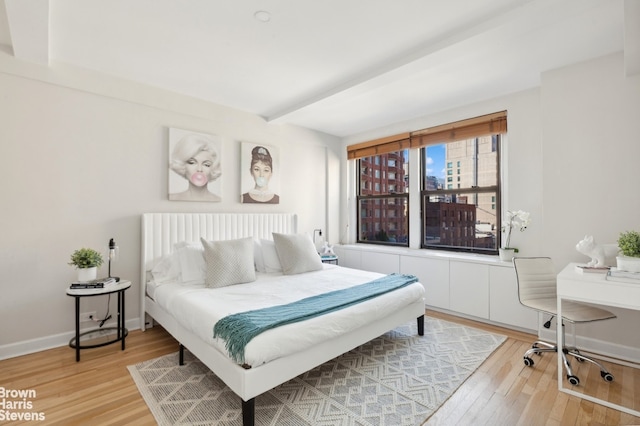 bedroom featuring light wood-type flooring, beam ceiling, and baseboards