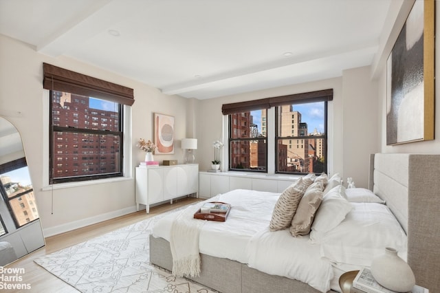 bedroom with a view of city, baseboards, and wood finished floors