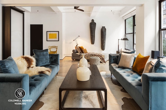 living area featuring beamed ceiling, light wood-style floors, and ceiling fan