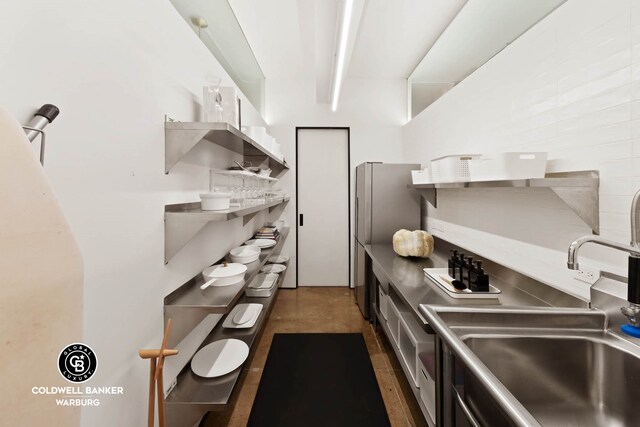 kitchen featuring a sink, open shelves, and freestanding refrigerator
