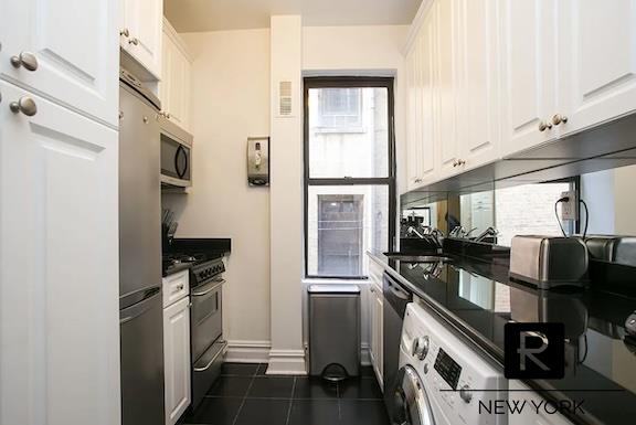 kitchen featuring appliances with stainless steel finishes, dark countertops, white cabinets, and dark tile patterned floors