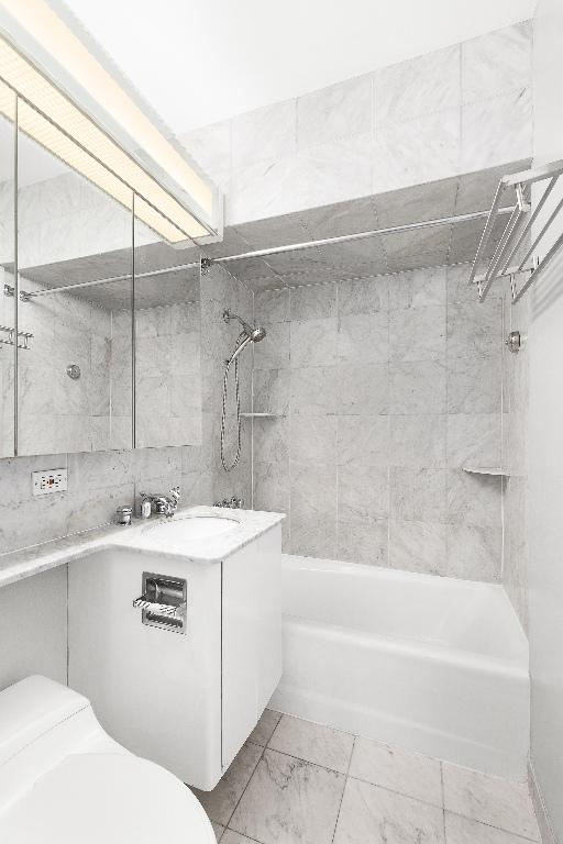 full bathroom with tiled shower / bath, vanity, and toilet