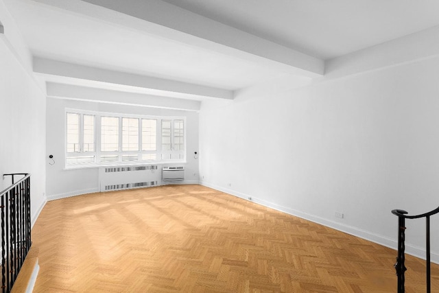 spare room featuring light parquet flooring, radiator, and beam ceiling