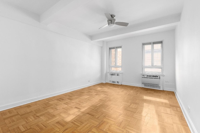 spare room with ceiling fan, beamed ceiling, light parquet flooring, and radiator heating unit