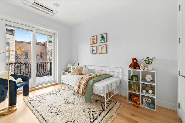 bedroom with light wood-type flooring and a wall mounted air conditioner