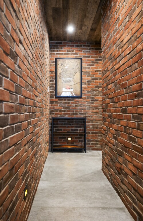 corridor featuring wood ceiling and brick wall