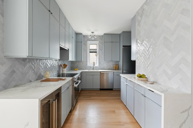 kitchen with beverage cooler, stainless steel appliances, sink, backsplash, and gray cabinetry