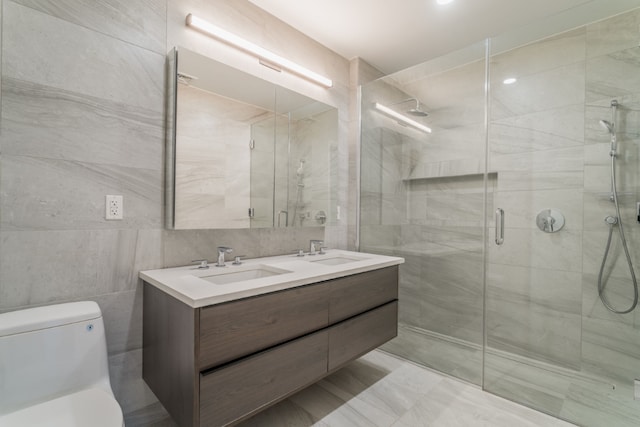 bathroom featuring vanity, toilet, a shower with door, and tile walls