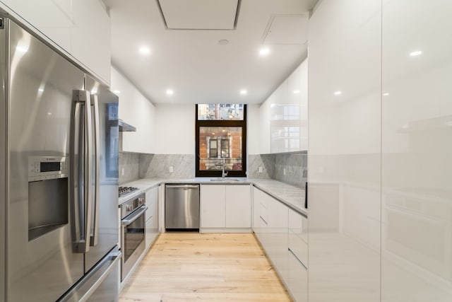 249 E 50th St Unit 7A, New York City, NY 10022 - kitchen featuring stainless steel appliances, modern cabinets, white cabinets, light wood finished floors, and backsplash