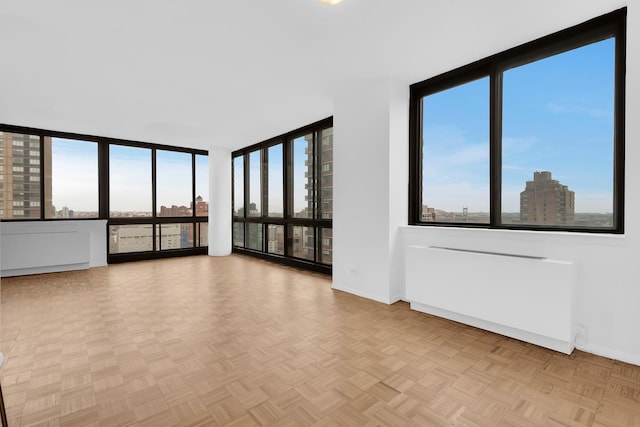 unfurnished room with expansive windows, baseboards, and a city view