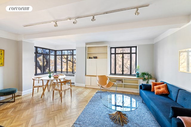 interior space with crown molding, light parquet flooring, radiator heating unit, and track lighting