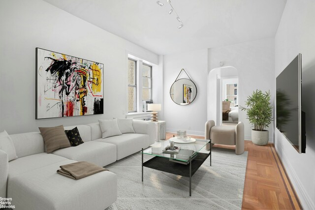 living area with arched walkways, baseboards, and rail lighting