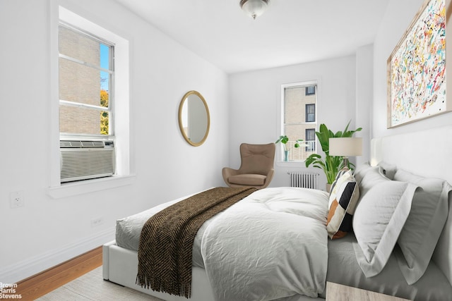 bedroom with radiator, wood finished floors, cooling unit, and baseboards