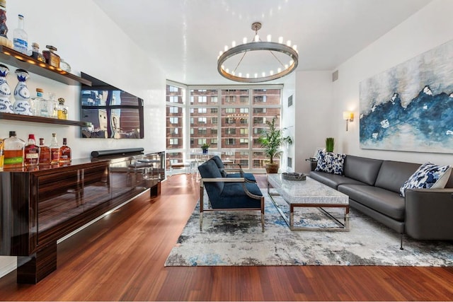 living room featuring wood-type flooring, a wall of windows, bar, and an inviting chandelier