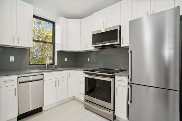 kitchen with white cabinetry, decorative backsplash, appliances with stainless steel finishes, and a sink