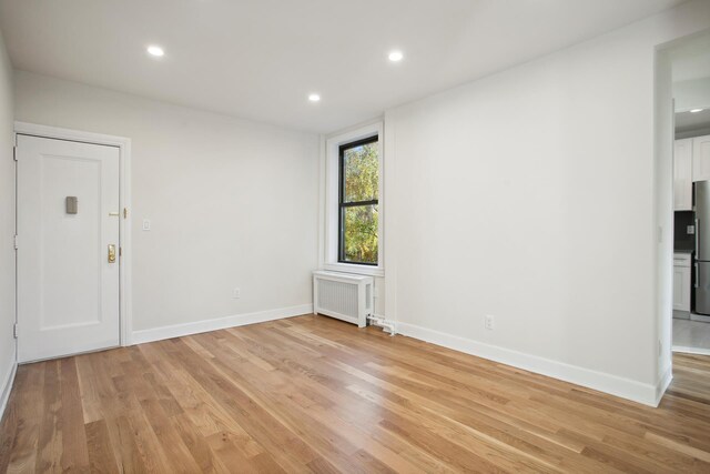 living room with radiator heating unit, electric panel, and light hardwood / wood-style floors