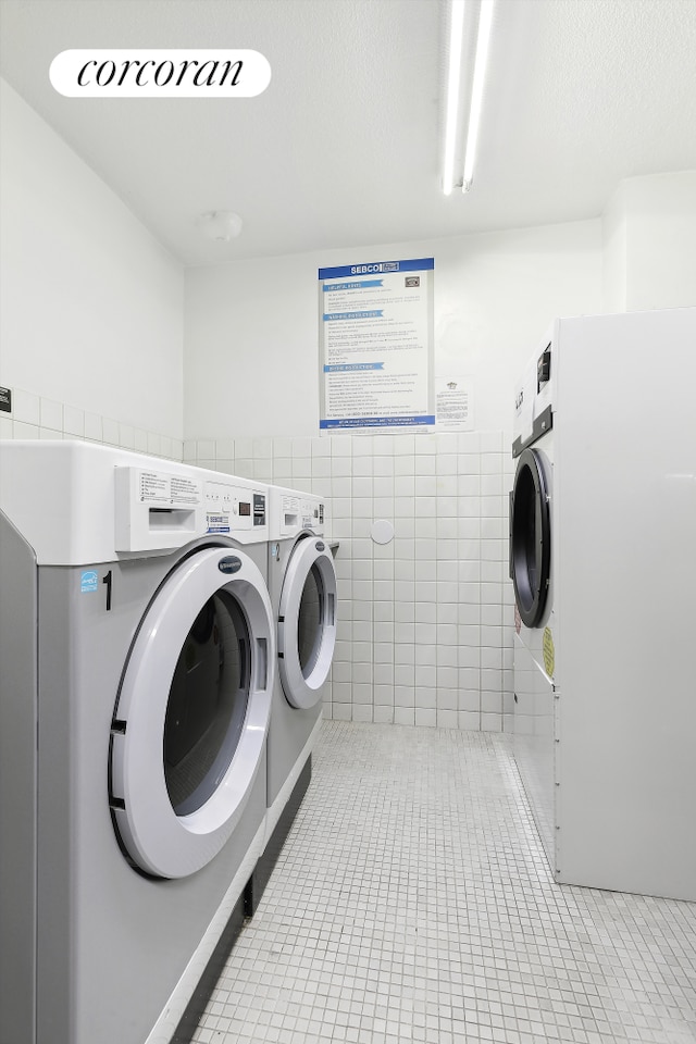 laundry room featuring washer and clothes dryer, laundry area, tile walls, and light tile patterned floors