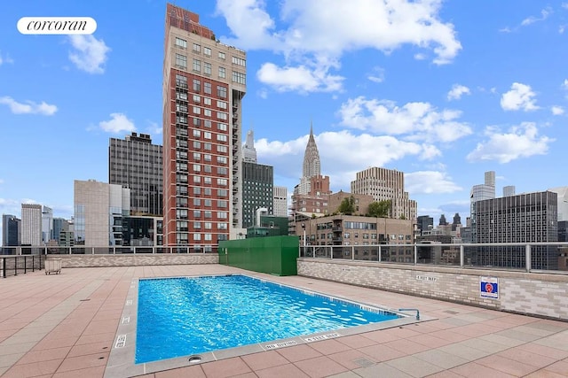 view of swimming pool featuring a patio and a city view