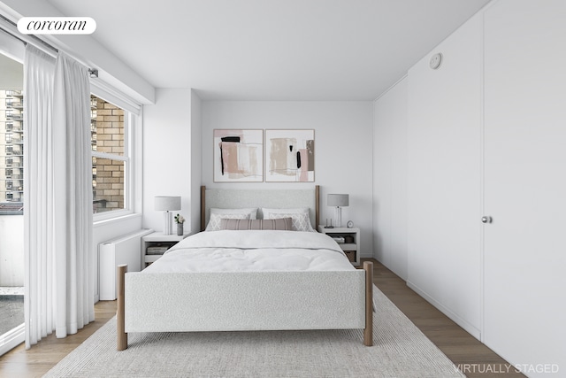 bedroom with wood finished floors and radiator heating unit